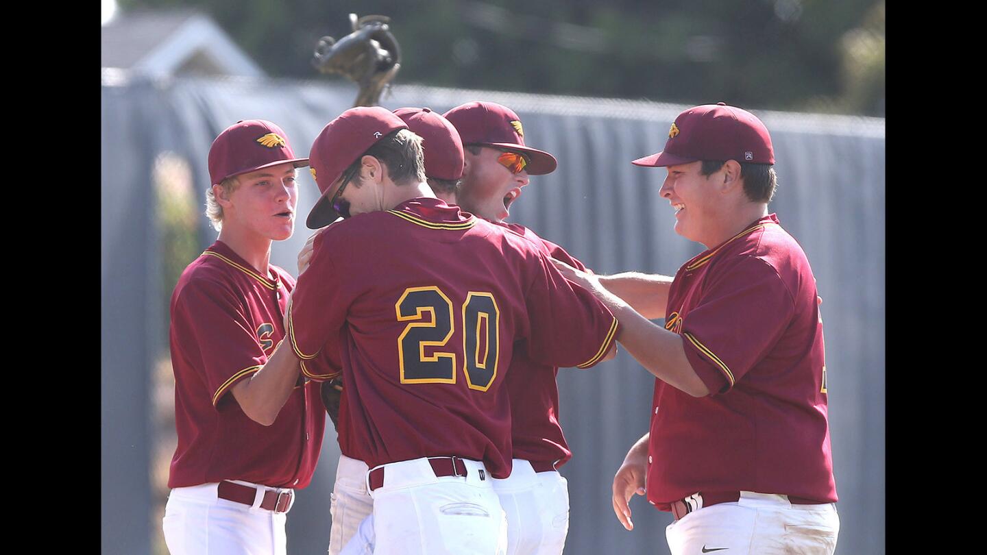 Members of the Estancia High baseball team including Jake Covey (20) gather around pitcher Nick Mazur, third from left after they won first round of the CIF Southern Section Division 5 playoffs against Anaheim at Estancia on Friday.