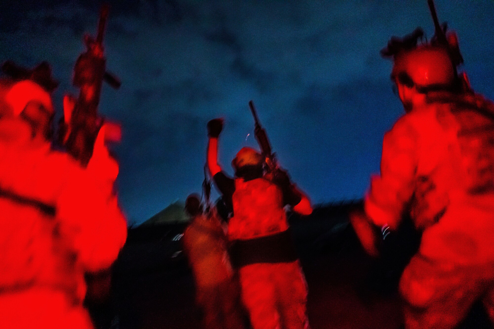 The backs of Taliban fighters illuminated red in the night, one fist raised, all of them with American gear, weaponry.