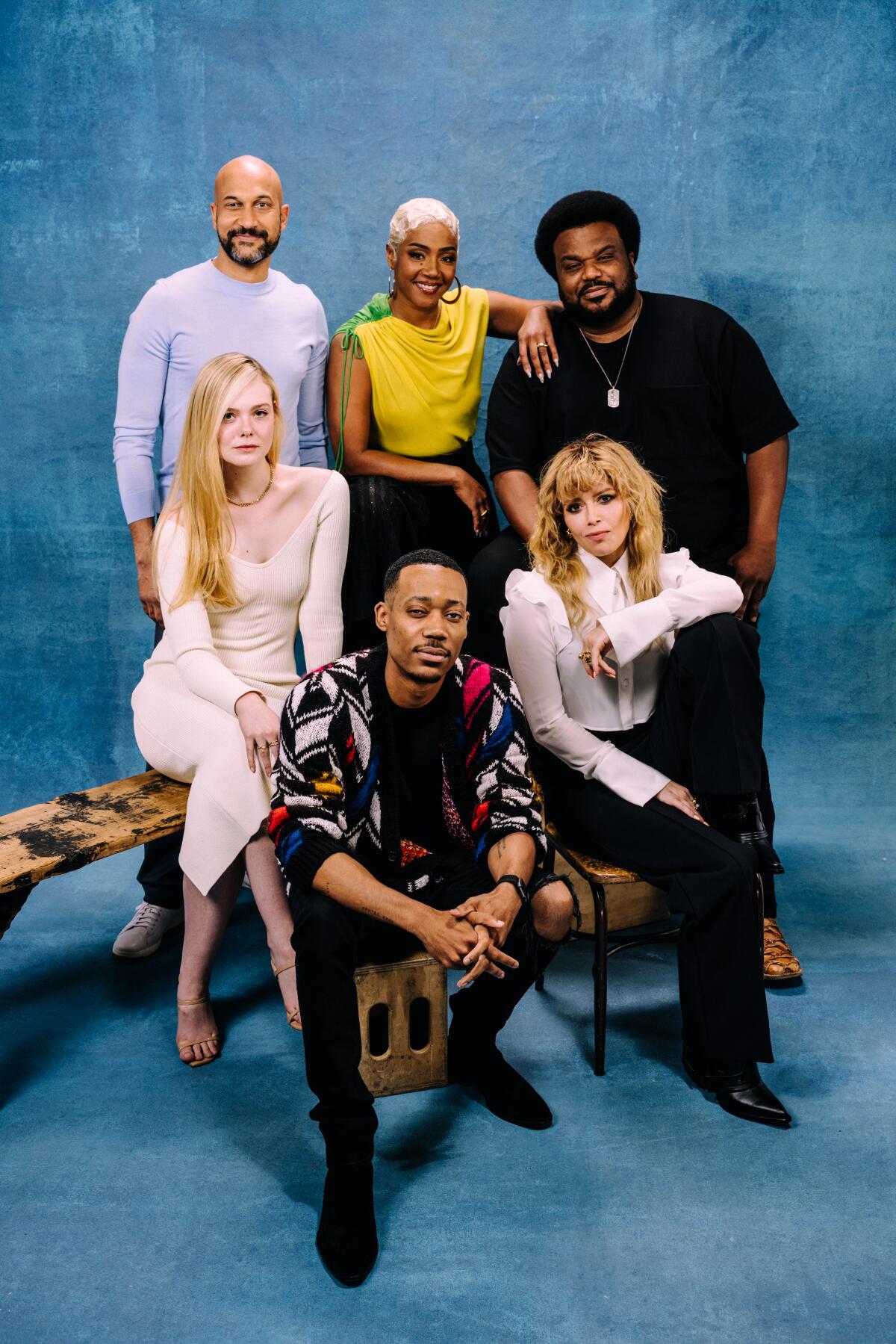 A group of six people poses for a portrait against a blue background.