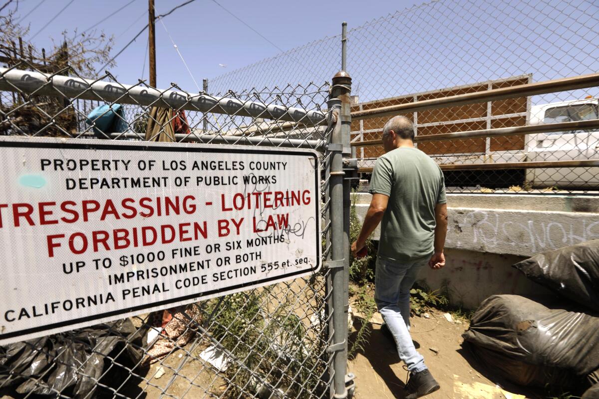 Gustavo Flores walks past a sign that states trespassing and loitering is forbidden by law on city property in Watts. 