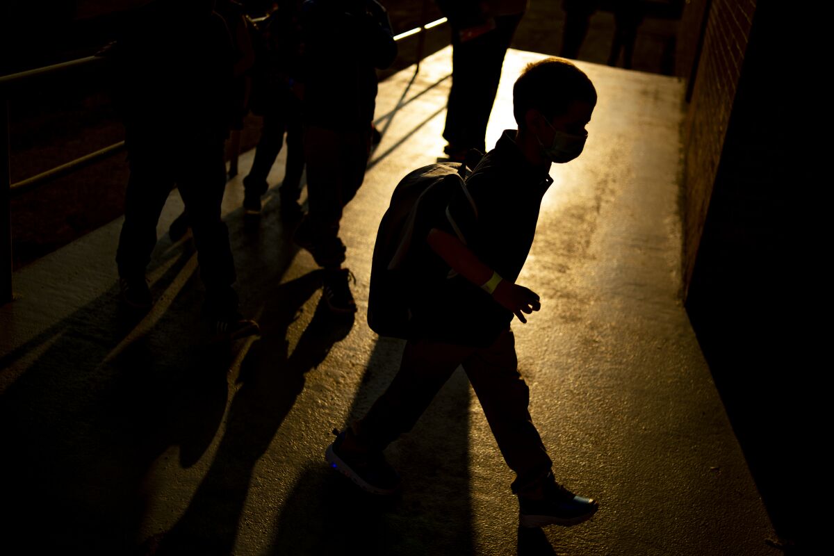 FILE - A student arrives as the sun rises during the first day of school on Wednesday, Aug. 4, 2021 at Freeman Elementary School in Flint, Mich. New autism numbers released Thursday, Dec. 2 suggest more U.S. children are being diagnosed with the developmental condition and at younger ages. (Jake May/The Flint Journal via AP, File)