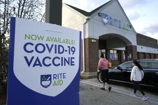 People walk past a COVID-19 vaccine sign as they enter a Rite Aid pharmacy in Nashua, N.H. 