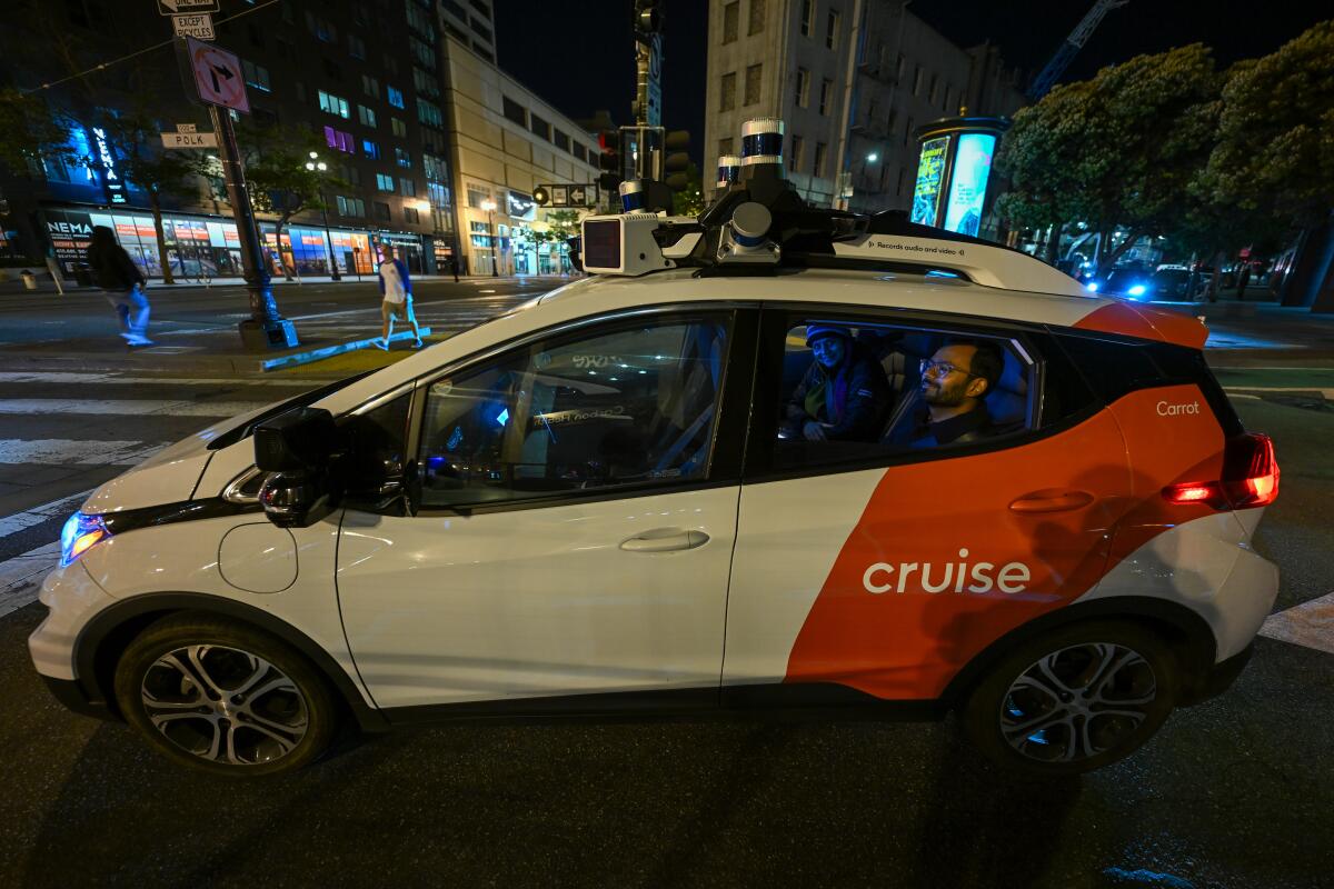 People sitting in the back of a white-and-orange car with the word Cruise on a road 