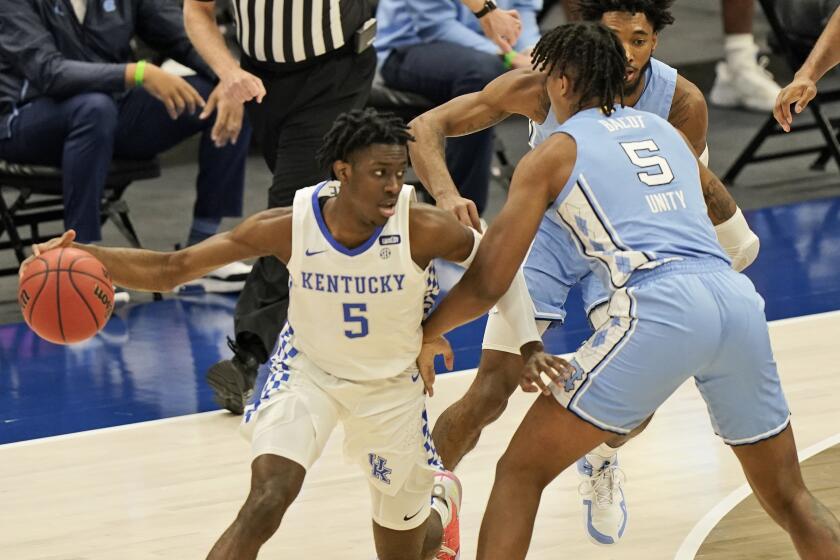 Kentucky's Terrence Clarke, left, drives past North Carolina's Armando Bacot in the first half of an NCAA college basketball game, Saturday, Dec. 19, 2020, in Cleveland. (AP Photo/Tony Dejak)