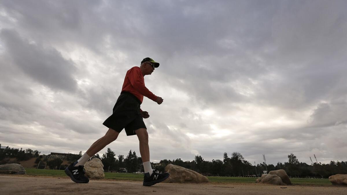 John Osmundson gets his speed walk in under foreboding skies as people work out around the Rose Bowl on Wednesday morning before a rainstorm was expected to hit.