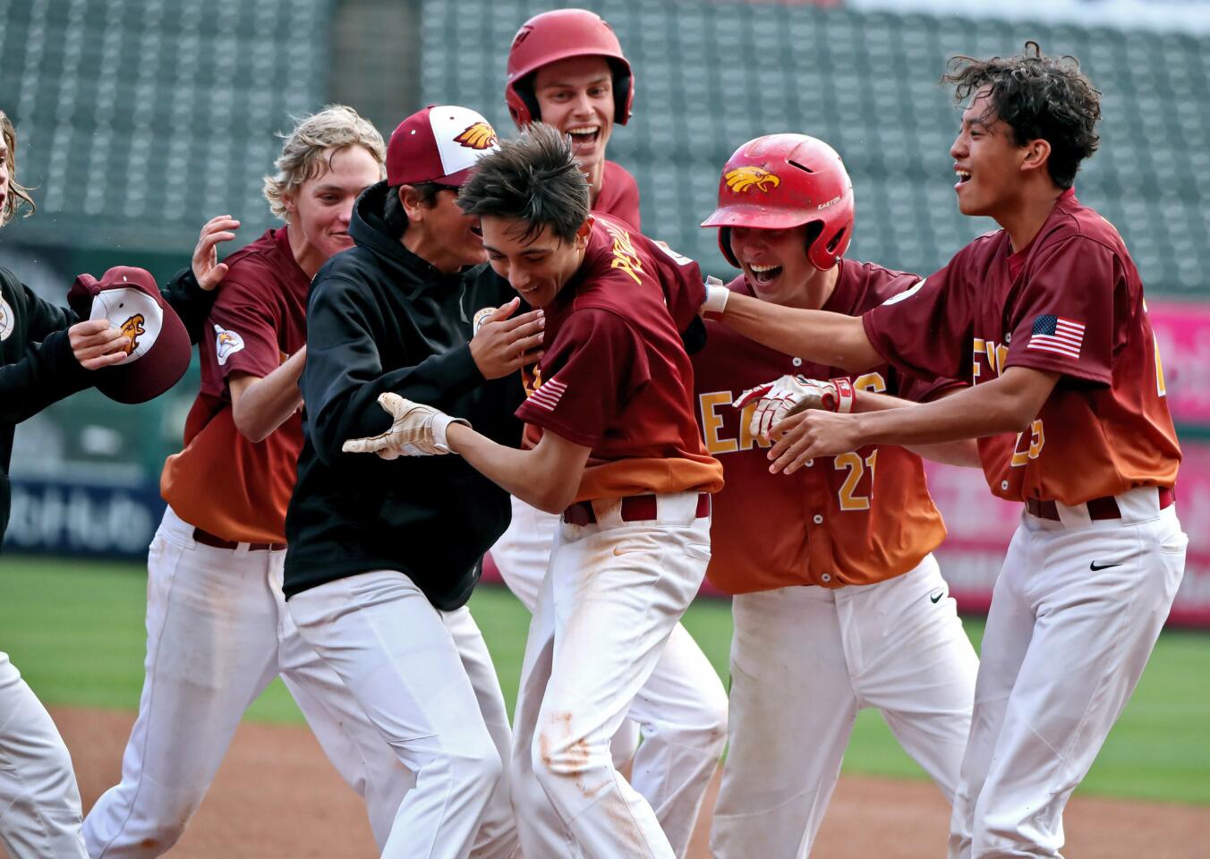 Estancia High's Nick Peralez, center, is mobbed by teammates after his walk-off hit in the bottom of the seventh inning lifted the Eagles to a 4-3 win over rival Costa Mesa in the Halo Classic at Angel Stadium on Wednesday.
