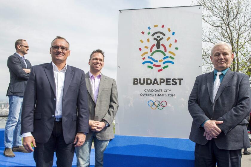 From left, Zsolt Borkai, president of the Hungarian Olympic Committee, Balazs Furjes, chairman of the Budapest 2024 bid, and Budapest Mayor Istvan Tarlos stand in front of the logo of host city candidate Budapest for the 2024 Olympics on Thursday.