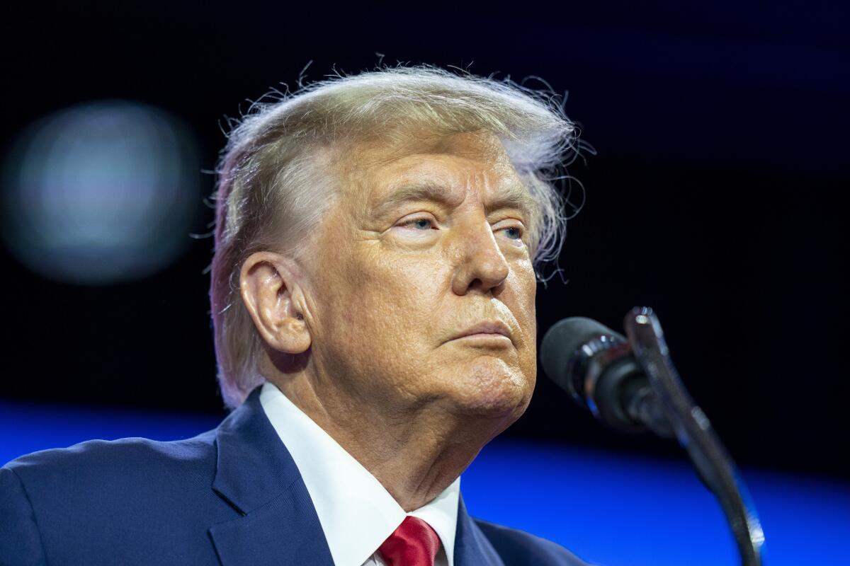 Former President Trump stands in front of a microphone 