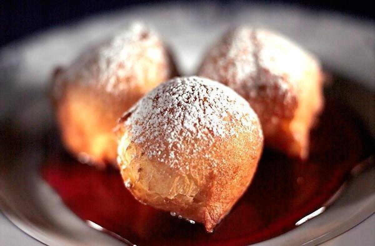Similar to fried doughnut holes, bumuelos here are served with sweet red wine sauce.