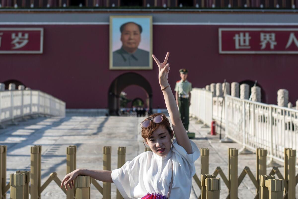 A tourist poses in front of a giant portrait of Mao Tse-Tung at the gate of the Forbidden City in Beijing on May 16, 2016. Official Chinese media stayed largely silent about the 50th anniversary of the start of the bloody Cultural Revolution, and discussion of the tumultuous decade is still controlled on the mainland.