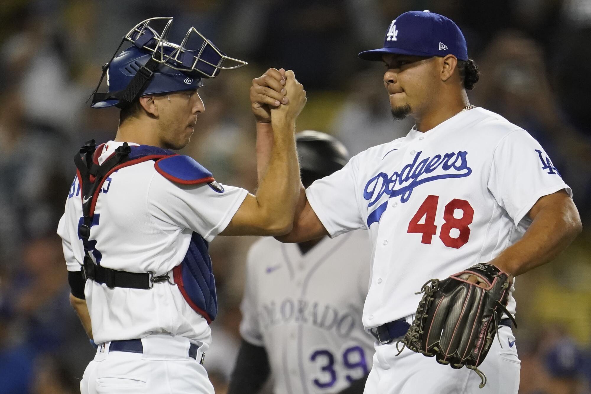 Dodgers catcher Austin Barnes and relief pitcher Brusdar Graterol shake hands in celebration.