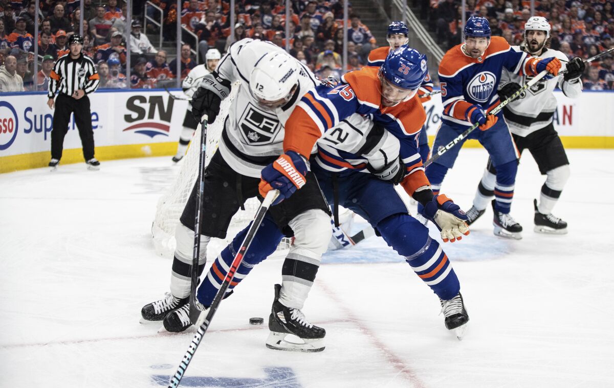 The Kings' Trevor Moore and the Edmonton Oilers' Darnell Nurse battle for the puck.