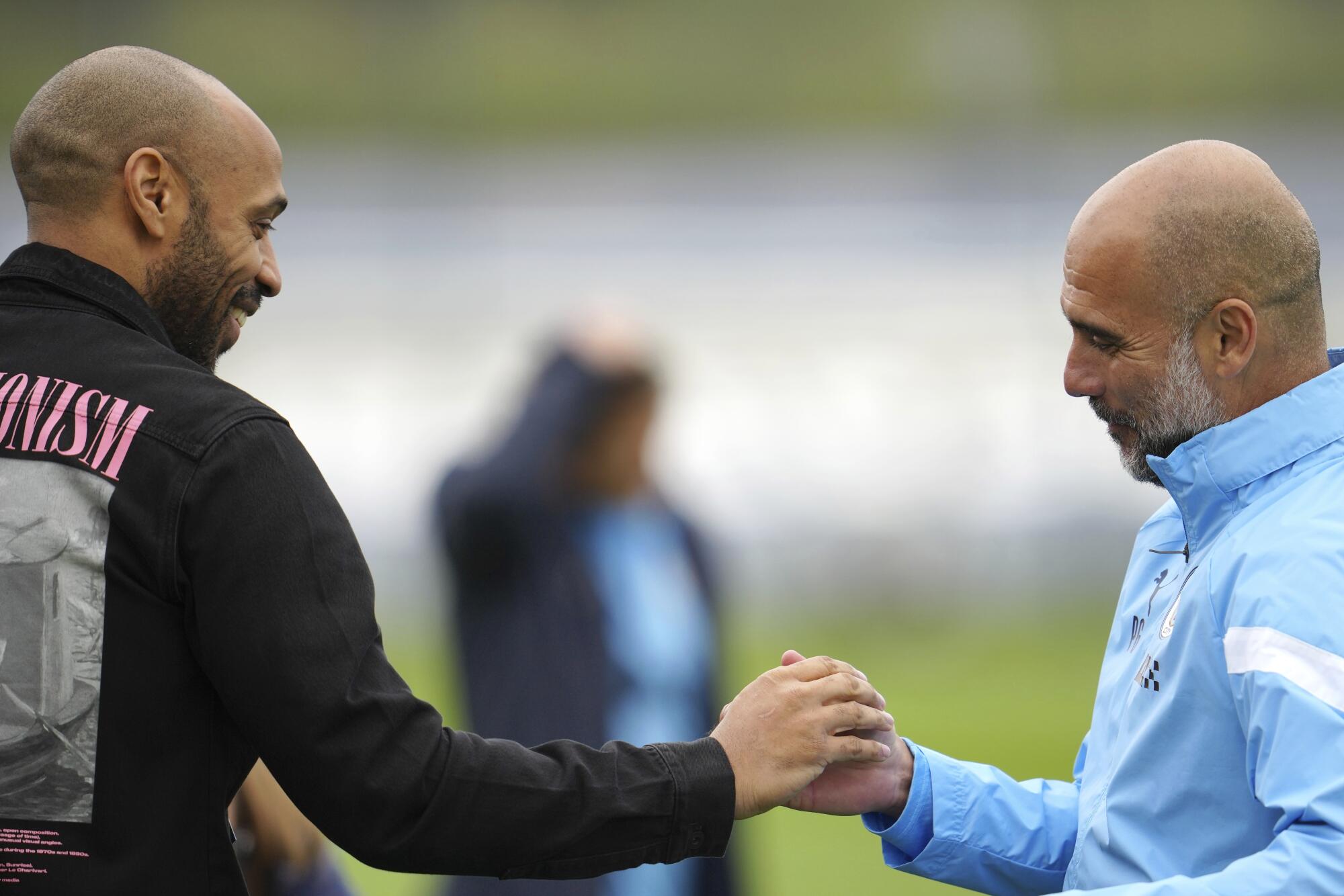 Manchester City coach Pep Guardiola shakes hands with former France and Arsenal striker Thierry Henry 