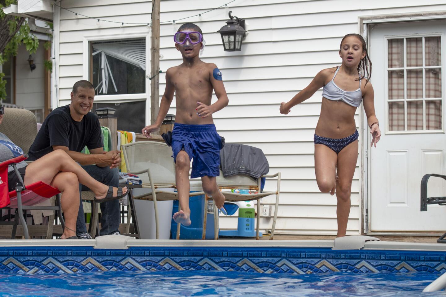 Carolyn and John Macan watch twins Bo and Brooklynn play in the family’s pool, which was donated by a local company.