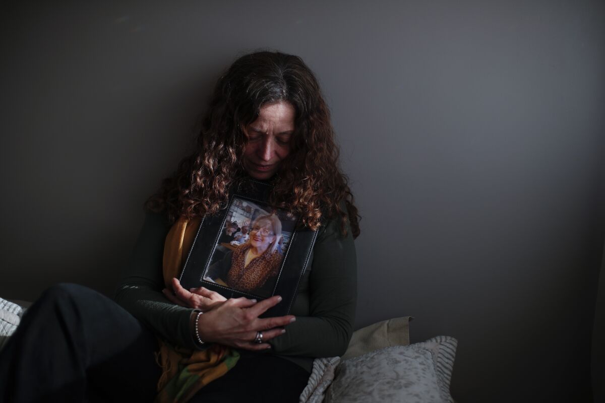 Argentine woman cradles a picture of her mother, who died of COVID-19.