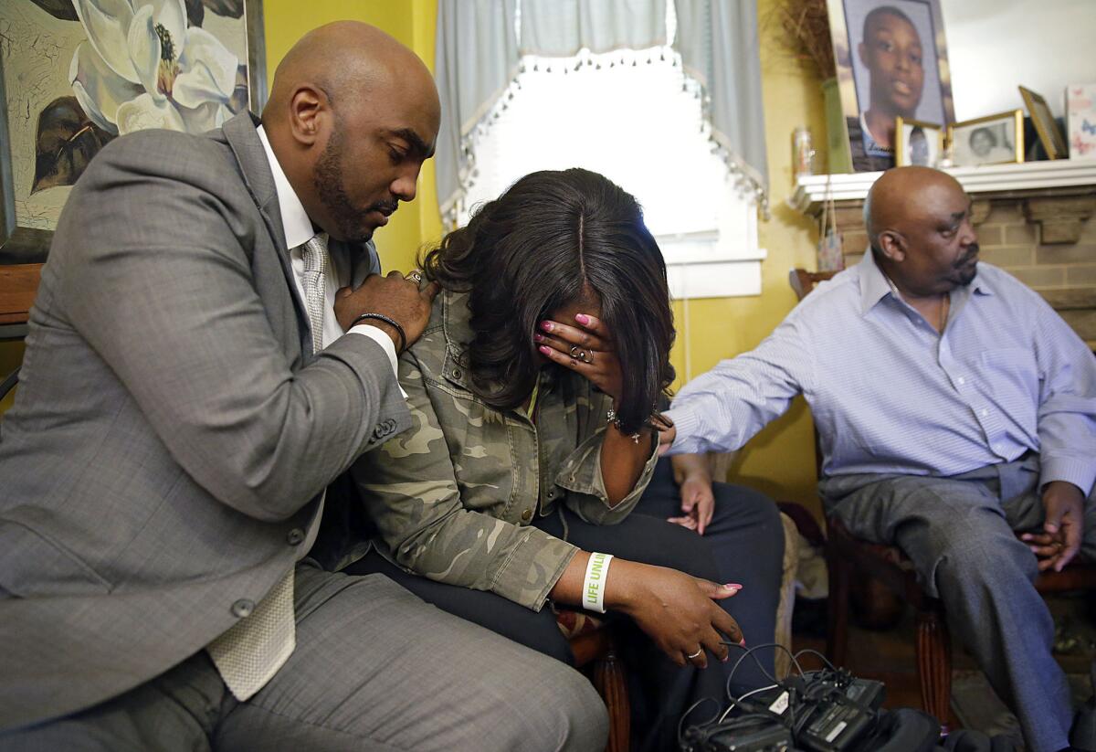 Attorney Damario Solomon-Simmons comforts Tiffany Crutcher, twin sister of Terence Crutcher, who was shot and killed by police in Tulsa, Okla., on Friday. At right is the Rev. Joey Crutcher, the twins' father.