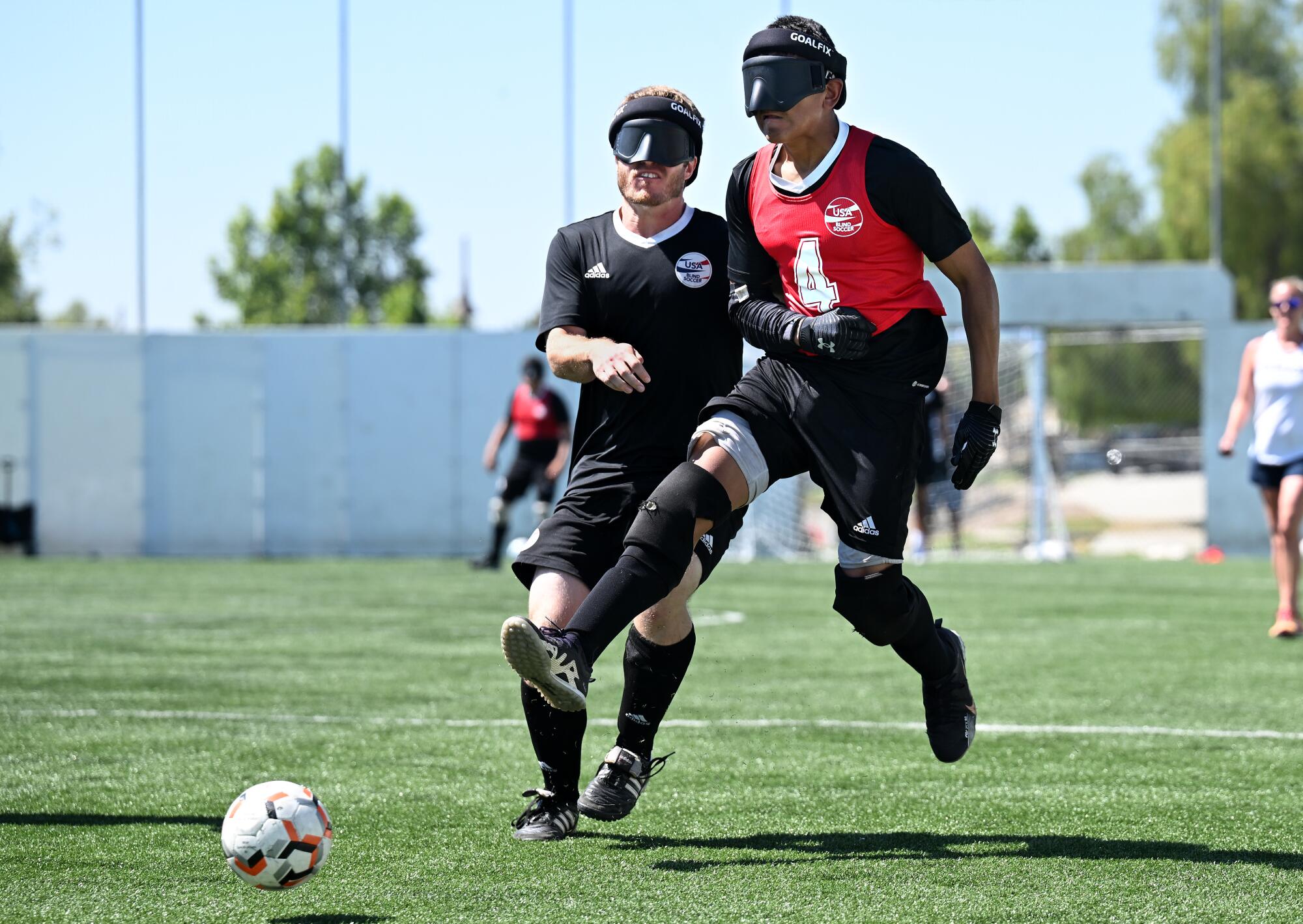 Blind soccer player Ricardo Castaneda takes a shot while running past Noah Beckman during a scrimmage 