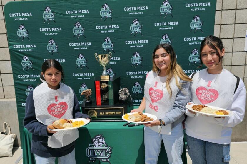 Costa Mesa athletes pose with a plate of food in front of the trophy at the All-Sports Cup luncheon on Tuesday at Costa Mesa High.