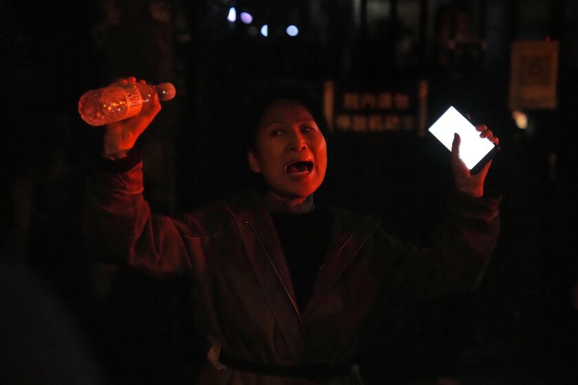 A woman shouts during a protest in Beijing, Sunday, Nov. 27, 2022. Protesters angered by strict anti-virus measures called for China's powerful leader to resign, an unprecedented rebuke as authorities in at least eight cities struggled to suppress demonstrations Sunday that represent a rare direct challenge to the ruling Communist Party. (AP Photo/Ng Han Guan)