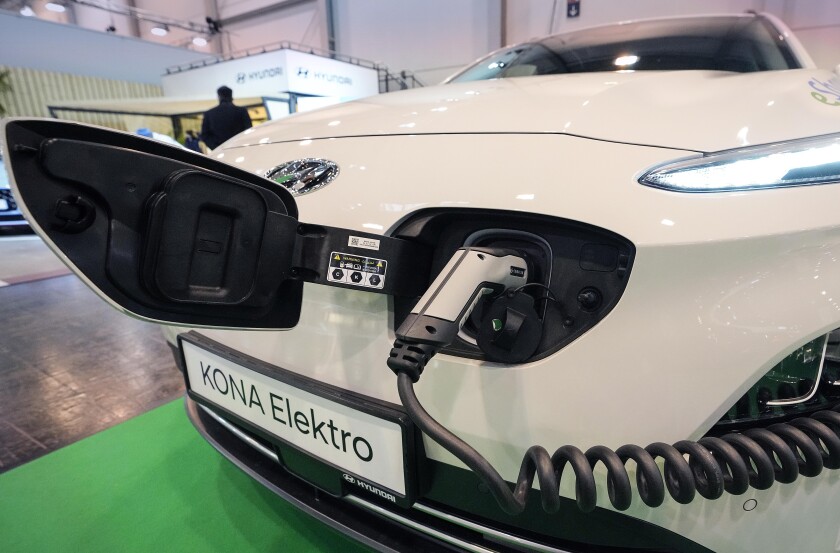 File - A Hyundai Kona electric car is charged at the Motor Show in Essen, Germany, Dec. 2, 2021. The German government said Monday it is extending the country's current system of incentive payments for buyers of electric and hybrid cars for a year, but will then impose tougher requirements for the vehicles that get support. (AP Photo/Martin Meissner, File )