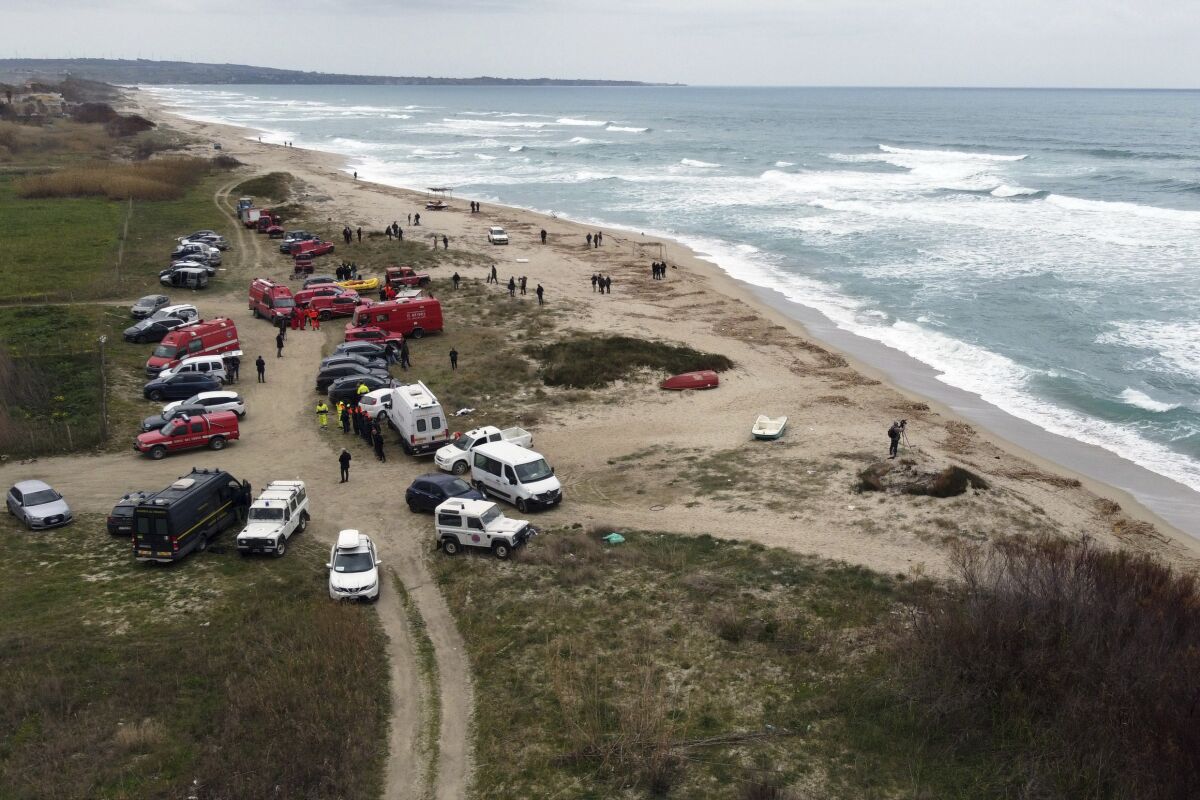 Firefighters search along a beach.