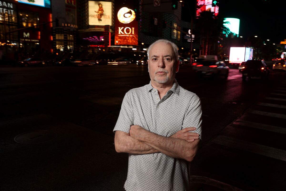 Jeff German stands on a dark street with lighted buildings in the background.
