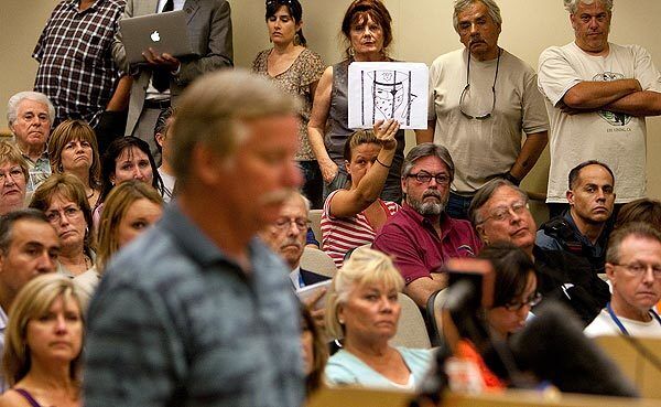 A woman holds a drawing of a police officer behind bars as Ron Thomas asks the Fullerton City Council for answers about his son Kelly's death. Residents packed the council chambers and an overflow area for the Aug. 2 meeting.