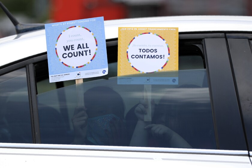 FILE - In this June 25, 2020, file photo, two young children hold signs through the car window that make reference to the 2020 U.S. Census as they wait in the car with their family at an outreach event in Dallas. A delay in census data is scrambling plans in some states to redraw districts for the U.S. House and state legislatures. The Census Bureau has said redistricting data that was supposed to be provided to states by the end of March won't be ready until August or September. (AP Photo/Tony Gutierrez, File)