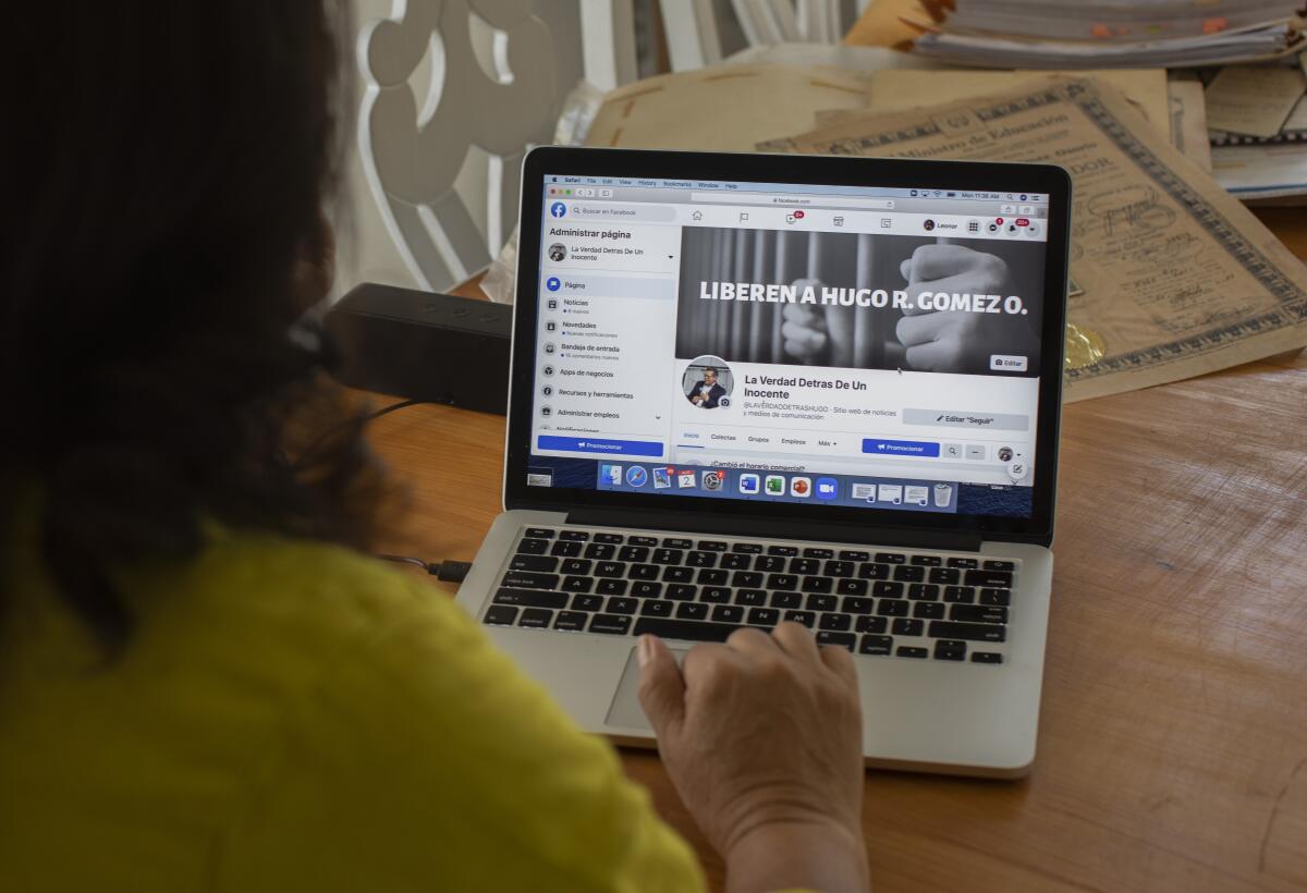 A woman is seated in front of an open laptop