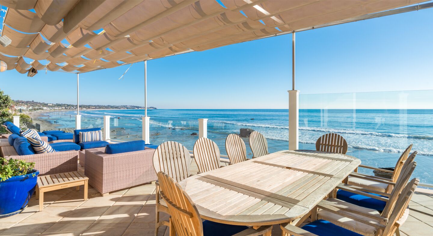 The covered dining deck has tables and chairs and an ocean view.