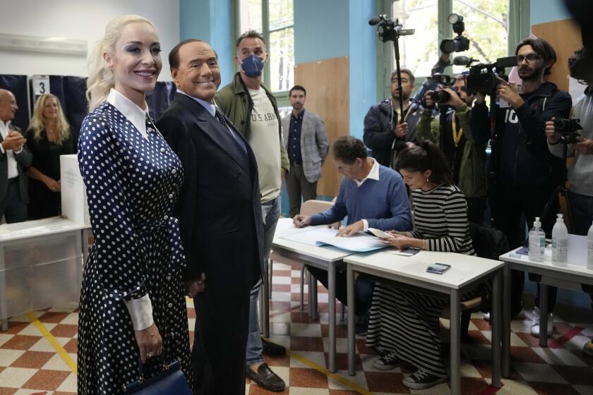 FILE - Silvio Berlusconi, leader of center-right, populist Forza Italia is flanked by his partner Marta Fascina, after casting his ballot at a polling station in Milan, Italy, Sunday, Sept. 25, 2022, in Milan, Italy. Just in time to celebrate his 86th birthday, Italy’s former premier Silvio Berlusconi is making his return to Italy's parliament, winning a seat in the Senate nearly a decade after being banned from public office over a tax fraud conviction. (AP Photo/Antonio Calanni, File)