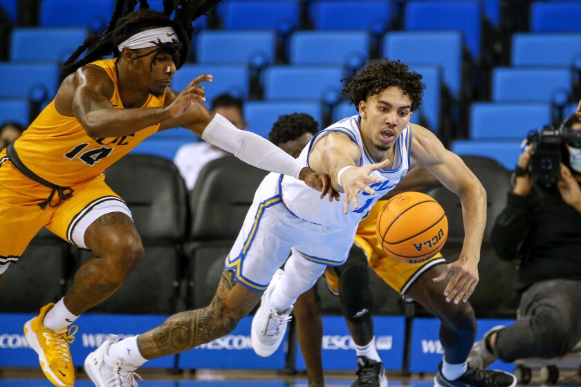 UCLA guard Jules Bernard, right, dives in an attempt to reach the ball next to Long Beach State guard Colin Slater during the second half of an NCAA college basketball game Thursday, Jan. 6, 2022, in Los Angeles. UCLA won 96-78. (AP Photo/Ringo H.W. Chiu)