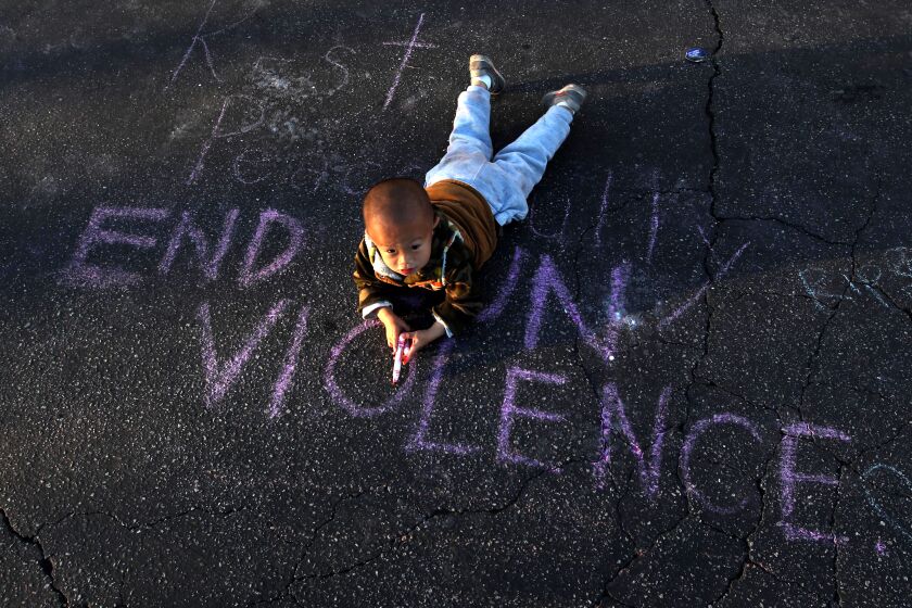 Harry Su, 2, lays on the message, "End Gun Violence," at the memorial outside the Star Ballroom Dance Studio