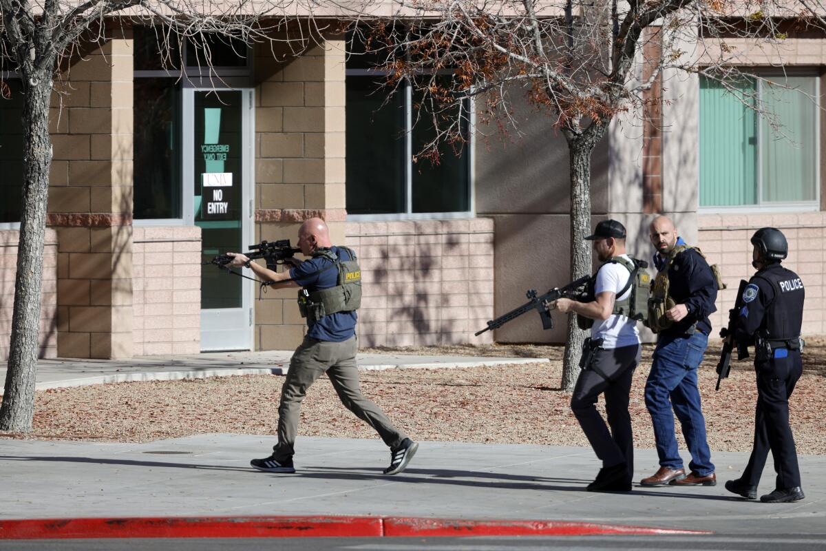 Law enforcement officers with rifles move toward a building.