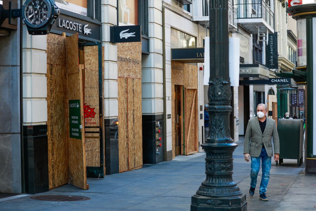 A man passes by boarded-up but open storefronts during the holiday season in Union Square in San Francisco.