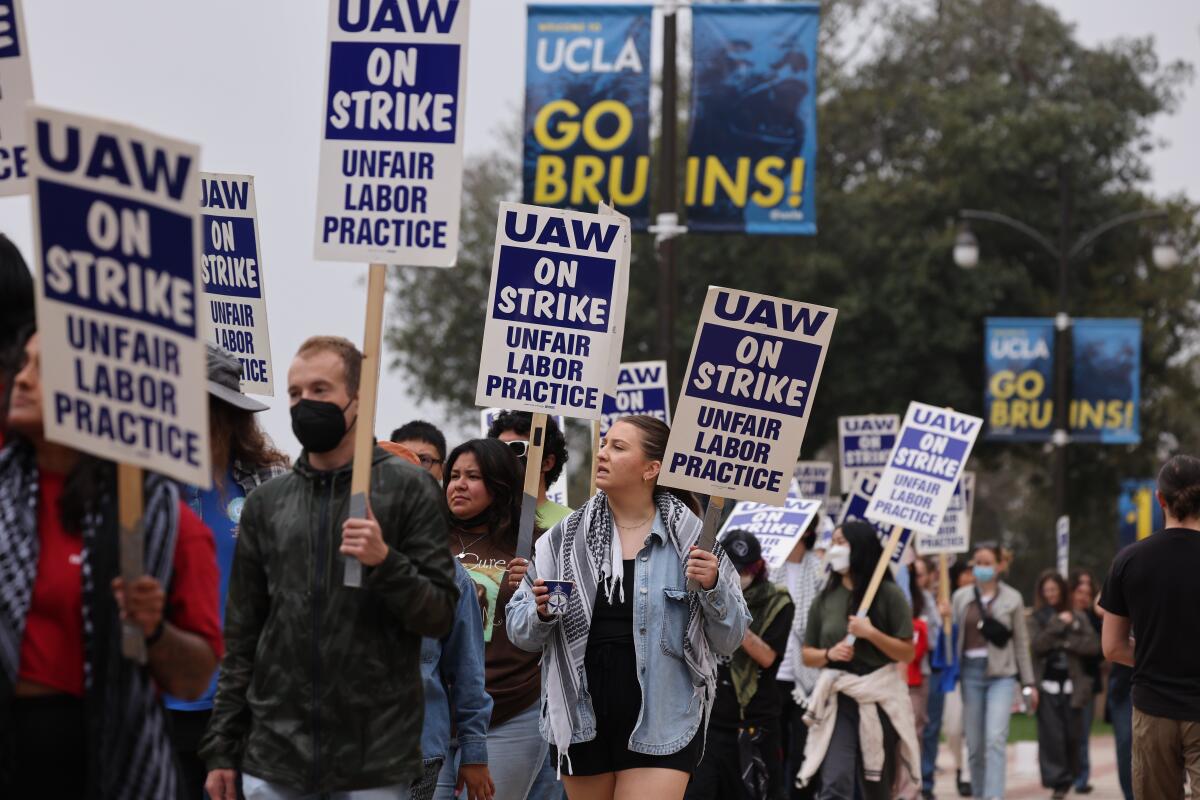 Academic workers at UCLA hold up picket signs.