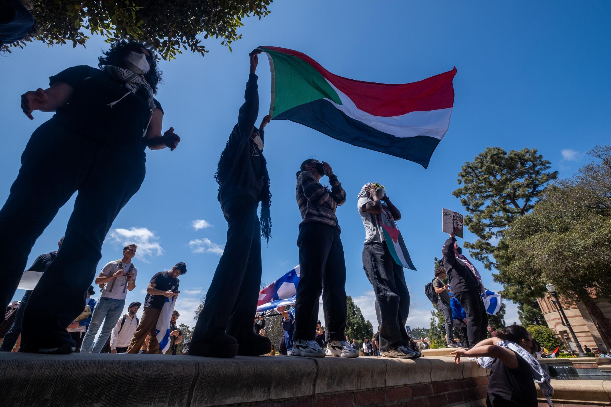 A pro-Palestine protester holds a flag near an encampment set up on the campus of UCLA.