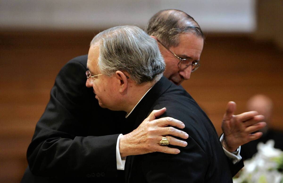 Cardinal Roger Mahony, left, hugs Archbishop Jose Gomez in 2010, the year before Gomez succeeded Mahony as head of the Los Angeles Archdiocese.