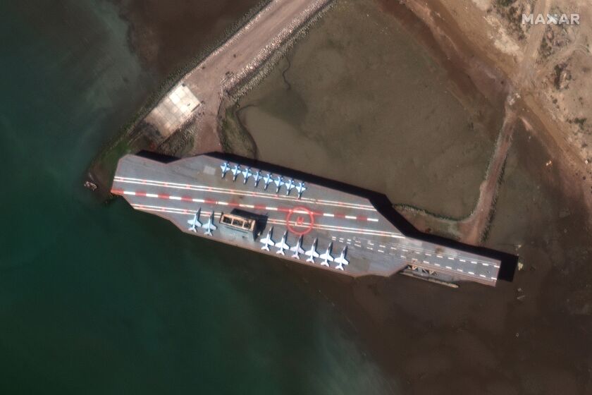 In this Feb. 15, 2020, satellite photo provided on July 27, 2020, by Maxar Technologies, a mockup aircraft carrier built by Iran is seen at Bandar Abbas, Iran, before being put to sea. Satellite photographs released Monday, July 27, showed Iran has moved the aircraft carrier out to sea likely for naval drills amid heightened tensions between Tehran and the U.S. (Maxar Technologies via AP)