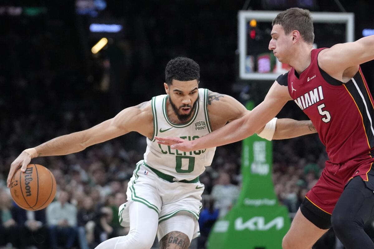 Celtics forward Jayson Tatum, left, tries to drive past Heat forward Nikola Jovic.
