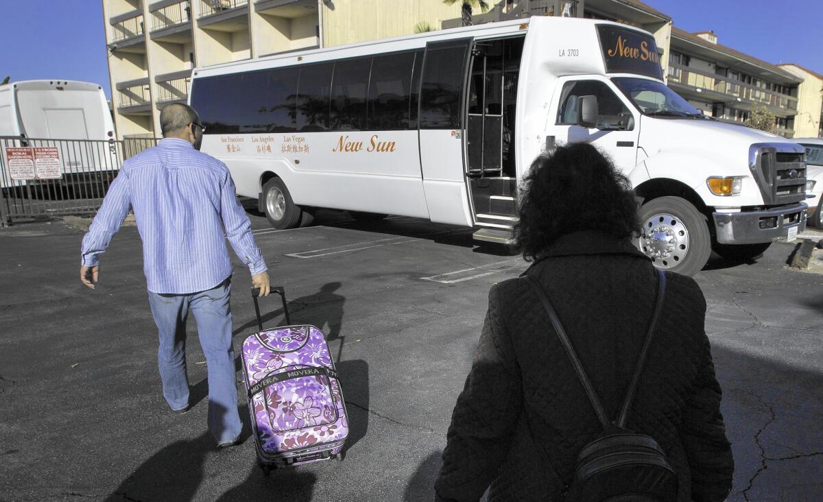 Passengers board a New Sun International Travel bus to Las Vegas from a hotel parking lot in Rosemead.