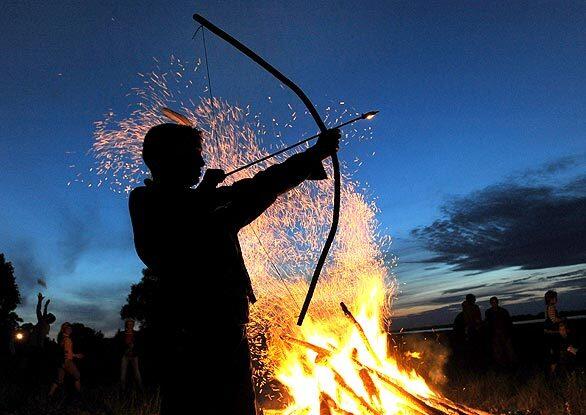 A Belarusian man shoots an arrow near a campfire while celebrating Ivan Kupala Night, a traditional Slavic holiday, in Turov.