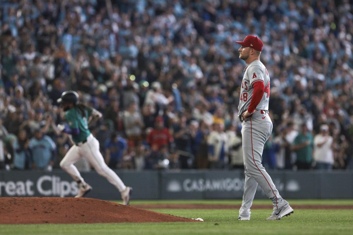 Angels starting pitcher Reid Detmers walks back to the mound as J.P. Crawford runs the bases after hitting a grand slam.