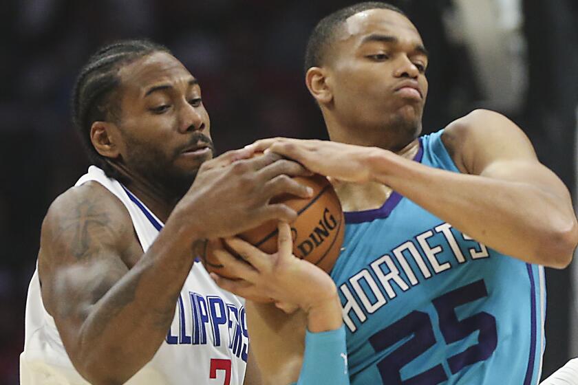Clippers forward Kawhi Leonard tries to wrestle the ball from Hornets forward PJ Washington during their game Monday night at Staples Center.