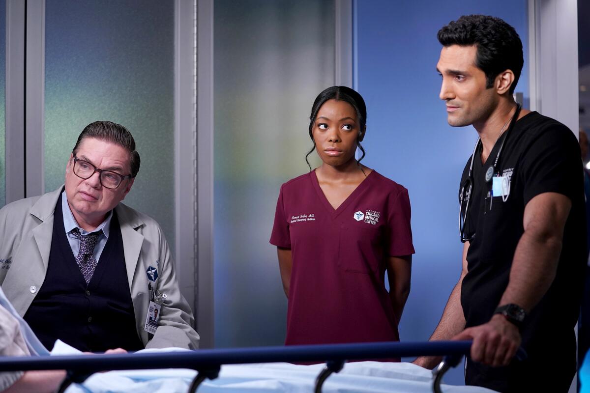 One female and two male doctors surround a bedside in "Chicago Med" on NBC.