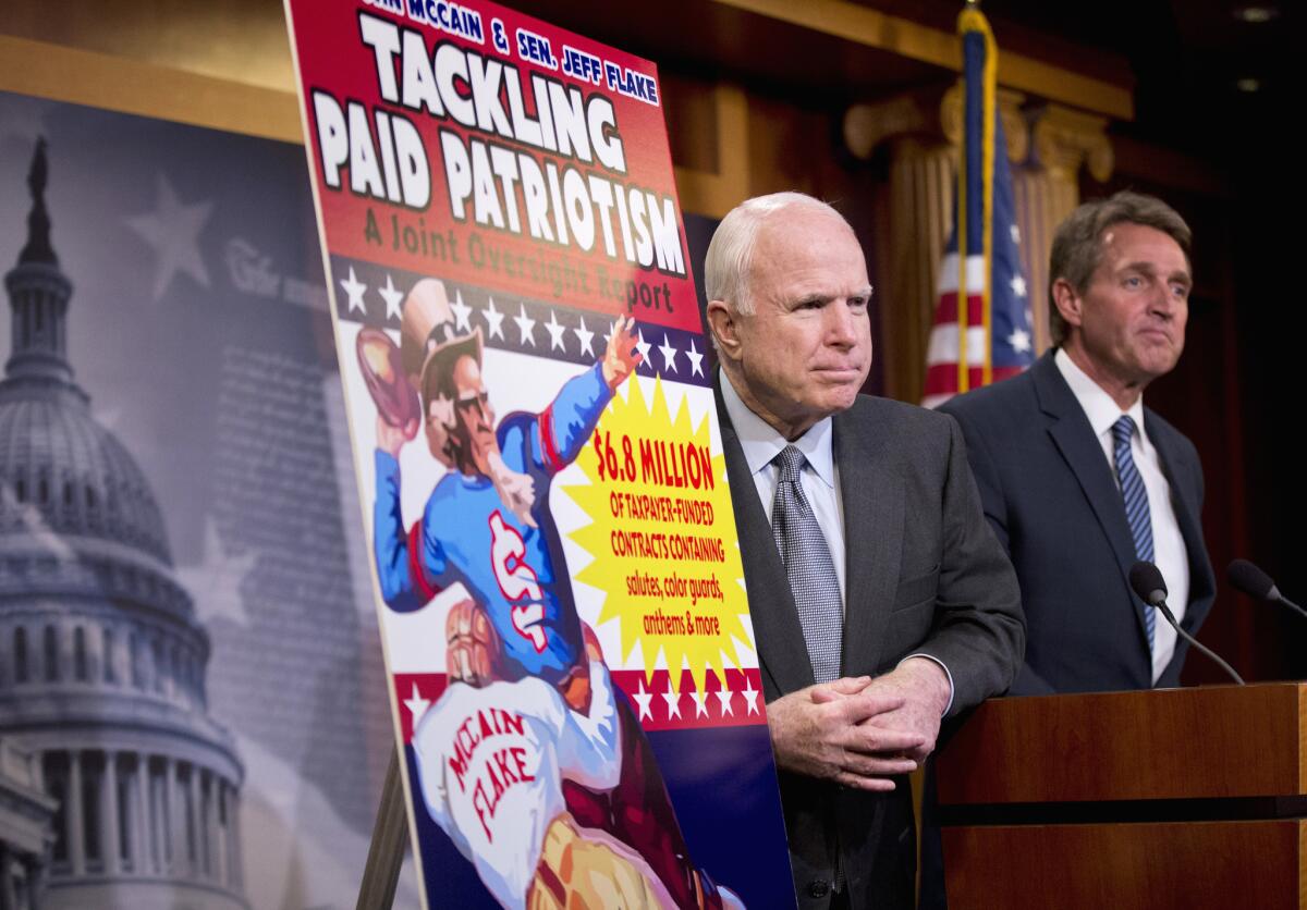 Sens. John McCain, left, and Jeff Flake, Republicans from Arizona, talk about “paid patriotism” during a news conference in Washington on Wednesday. The senator detailed evidence in a report of the Pentagon paying pro teams to honor soldiers at games.