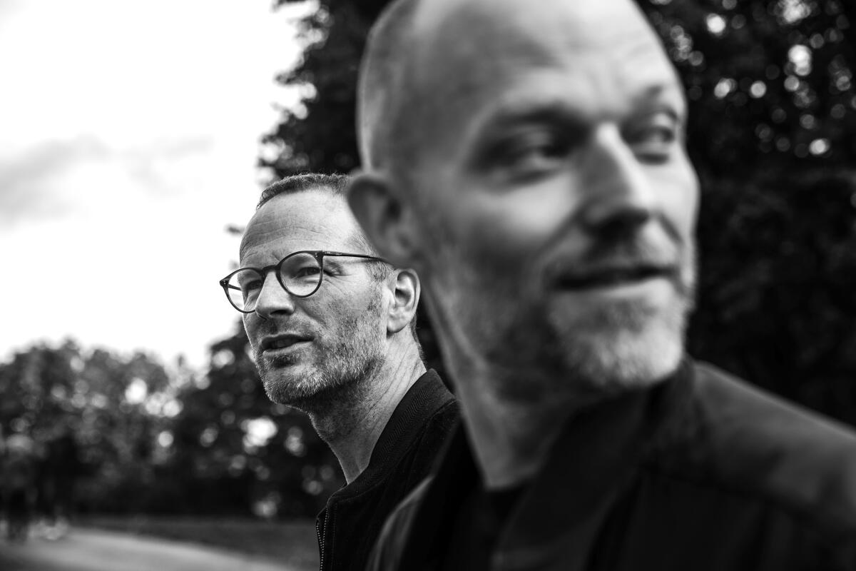 A black-and-white photo of friends Joachim Trier and Eskil Vogt outside together.