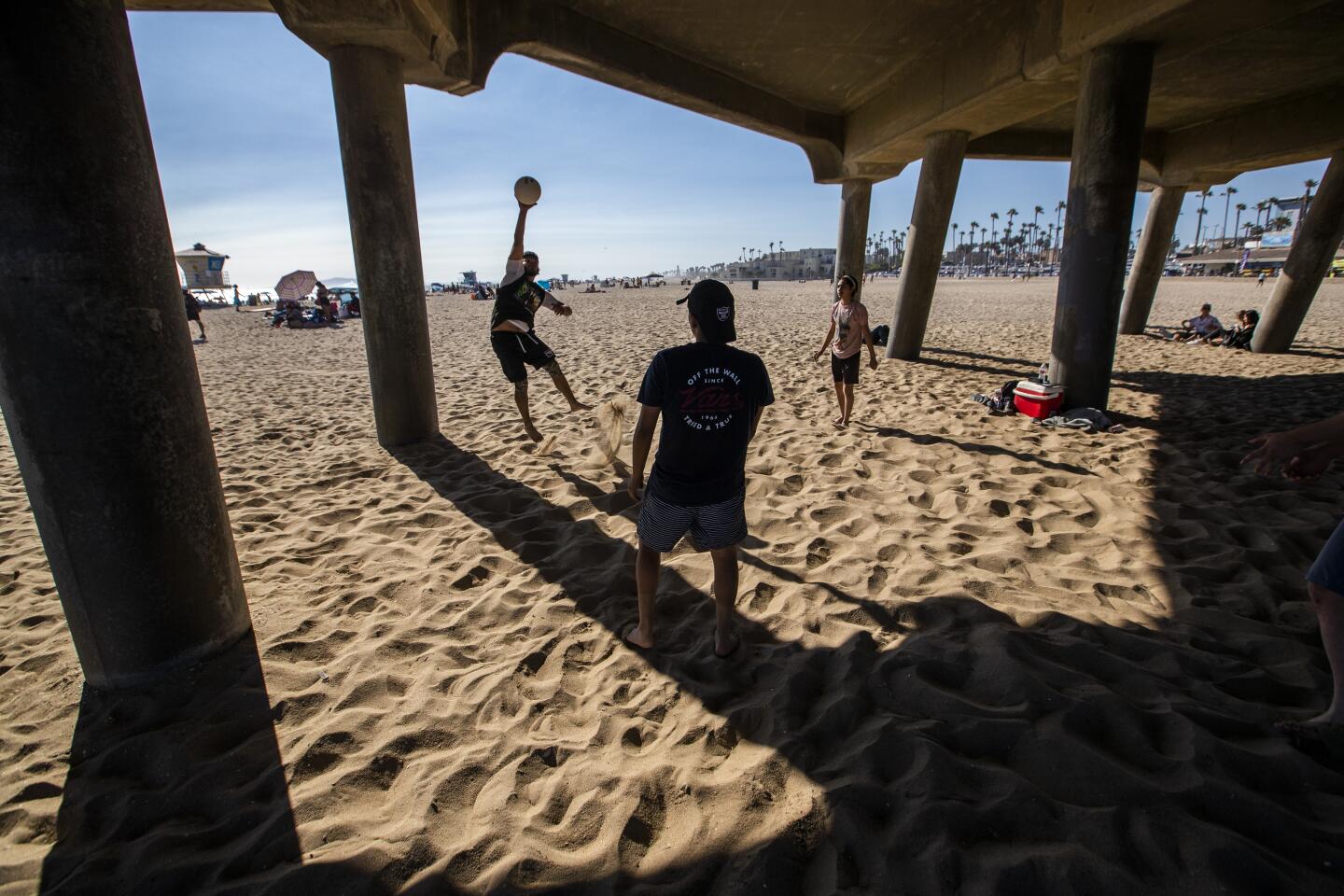 HUNTINGTON BEACH, CA - JUNE 10: Jorge Tafolla, of Los Angeles, hits a volleyball around with friends in the shade of the pier to cool off amid high temperatures Wednesday, June 10, 2020 in Huntington Beach, CA. A heat advisory will be in effect today from 11 in the morning until 7 tonight throughout Southern California. (Allen J. Schaben / Los Angeles Times)