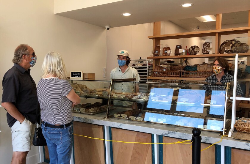 Siblings Clinton Prager, right, and Louie Prager, second from right, wait on customers Saturday, April 25, at their newly opened Prager Bros. Artisan Breads store in downtown Encinitas. Despite opening the shop during the pandemic on April 17, the brothers say the shop has been surprisingly busy.