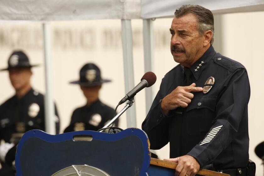 LAPD Chief Charlie Beck points to the mourning band worn by officers during a graduation ceremony for 37 officers Friday morning at LAPD headquarters.